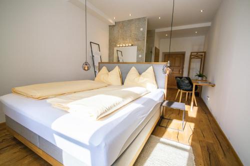 a large white bed in a room with a chair at Maria Waldrast in Matrei am Brenner