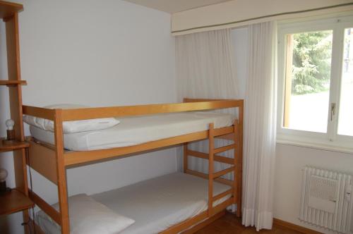 Cette chambre comprend 2 lits superposés et une fenêtre. dans l'établissement CRANS MONTANA LE REGENT APPARTEMENT, à Crans-Montana