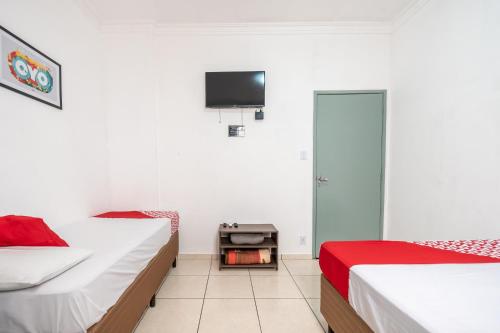 1 dormitorio con 2 camas y TV en la pared en Hotel Florencio, en Santo André