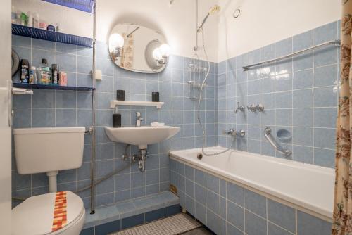 Baño de azulejos azules con aseo y lavamanos en Private Apartment, en Hannover