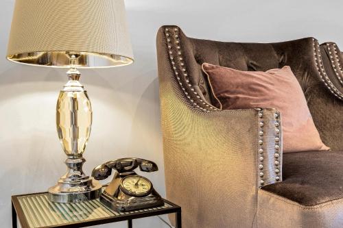 a lamp on a table next to a chair with a clock at St Martins 2 Bedroom Apartments in Ruislip By 360 Stays in Ruislip