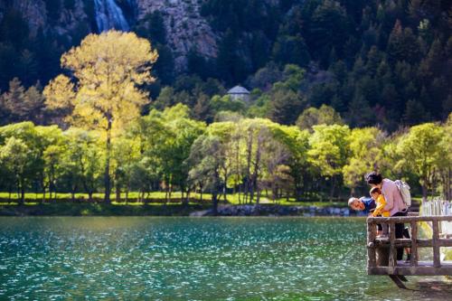 a man and a child sitting on a fence near a lake at Hotel Continental Balneario de Panticosa in Panticosa