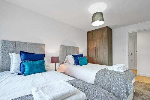 a bedroom with two beds with blue pillows at St Martins 2 Bedroom Apartments in Ruislip By 360 Stays in Ruislip