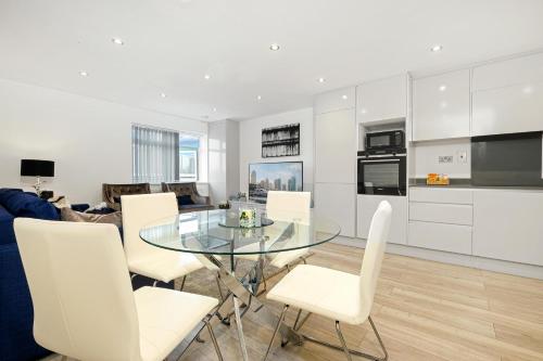 a kitchen and living room with a glass table and white chairs at St Martins 2 Bedroom Apartments in Ruislip By 360 Stays in Ruislip