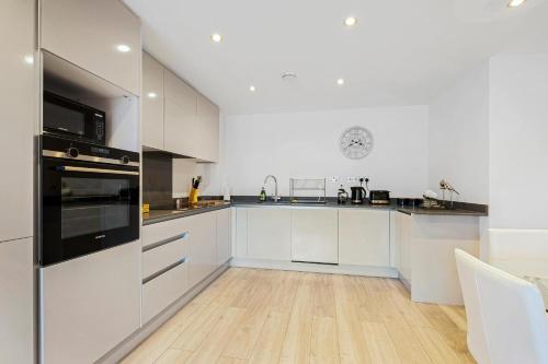 a kitchen with white cabinets and black appliances at St Martins 2 Bedroom Apartments in Ruislip By 360 Stays in Ruislip