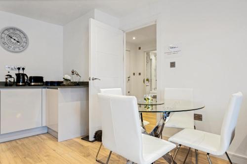 a kitchen and dining room with a glass table and white chairs at St Martins 2 Bedroom Apartments in Ruislip By 360 Stays in Ruislip