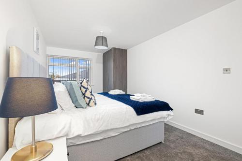 a bedroom with a bed with a lamp and a window at St Martins 2 Bedroom Apartments in Ruislip By 360 Stays in Ruislip