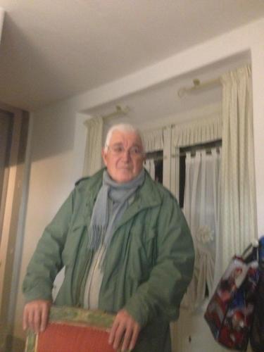 een oudere man staat in een kamer en houdt een doos vast bij Armonie di Villa Incontri B&B in Florence