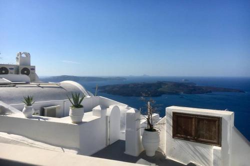a balcony with potted plants and a view of the ocean at Stefani Cave House Santorini in Firostefani