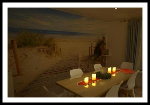 a dining room with a table and a painting of the beach at Nordstern in Büdelsdorf