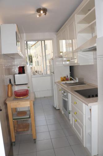 Il comprend une cuisine avec des placards blancs et du carrelage blanc. dans l'établissement Appartement T3 Climatisé entre mer et centre Nice, à Nice