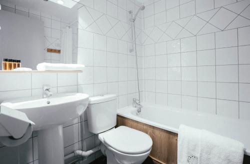 a bathroom with a toilet and a sink and a tub at Langley Hôtel Victors in Val-d'Isère