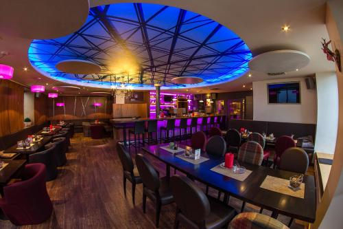 a restaurant with tables and chairs and a blue ceiling at Wohlfühlhotel Schiestl in Fügen