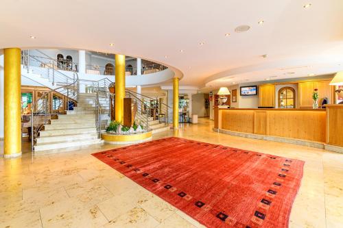 a lobby with a red rug in the middle of a building at Wohlfühlhotel Schiestl in Fügen