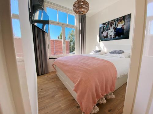 a bedroom with a bed and a large window at Luxurious historical Loft close to the beach!! in Wassenaar