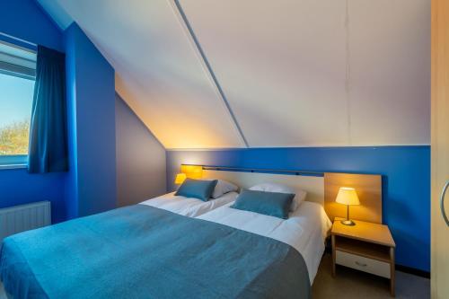 1 dormitorio azul con 2 camas y ventana en Antibes 280 - Kustpark Village Scaldia, en Hoofdplaat