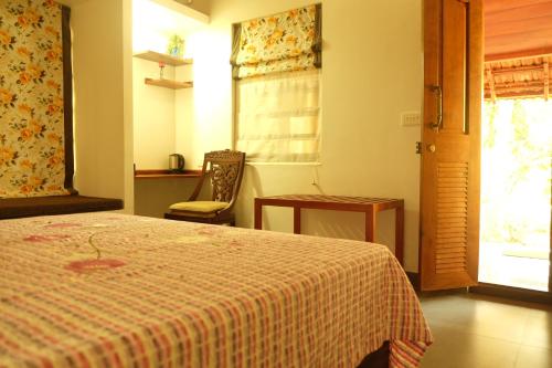 a bedroom with a bed and a chair and a window at Tarana Homestay in Gonikoppal
