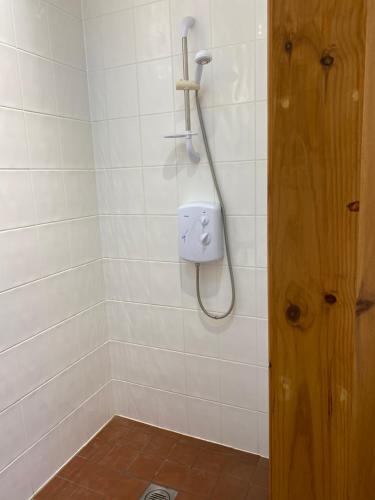a bathroom with a shower with a phone on the wall at The little crab hut in Sheringham