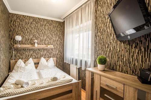 - une chambre avec un lit et une télévision murale dans l'établissement MF Club 218 Golden Beach Wellness Apartment, à Siófok