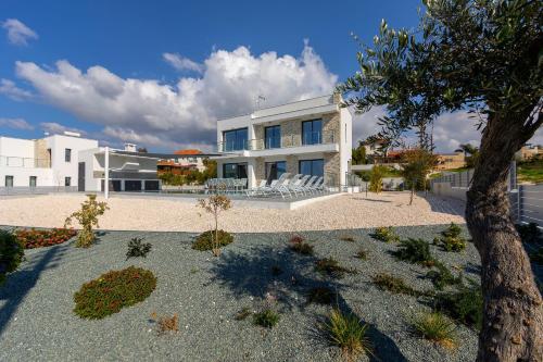 a large white house with a tree in front of it at Villa Andromeda, Sea Caves in Peyia
