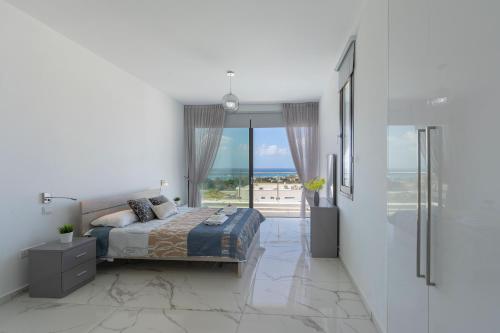 a bedroom with a bed and a view of the ocean at Villa Andromeda, Sea Caves in Peyia