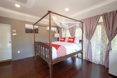 a bedroom with a canopy bed with red and white pillows at Capital O 75378 Thawapee Resort in Rayong