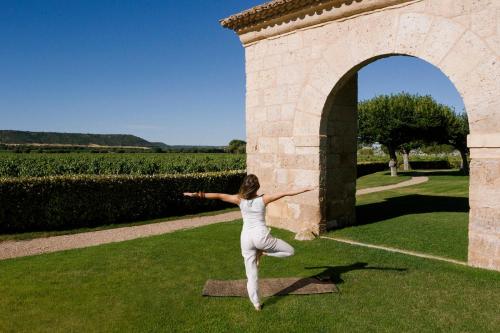 a woman doing yoga in the grass near an arch at Abadia Retuerta LeDomaine in Sardoncillo