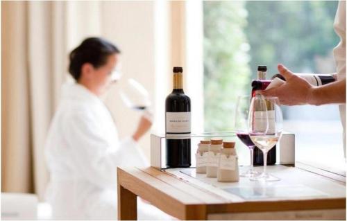 a person pouring a glass of wine and a woman in a bath room at Abadia Retuerta LeDomaine in Sardoncillo