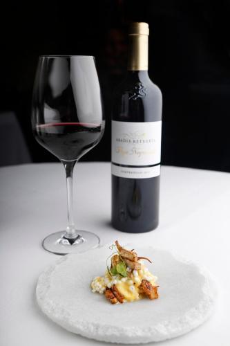 a bottle of wine and a plate of food and a wine glass at Abadia Retuerta LeDomaine in Sardoncillo