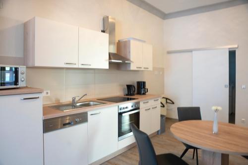 a kitchen with white cabinets and a wooden table with a dining room at Niedersburger Eck, wandern, radfahren, genießen, erholen in Boppard