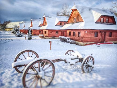 a snow covered yard with a wooden barn with snow covered cannons at Hotel Koliba Greta in Liptovská Sielnica