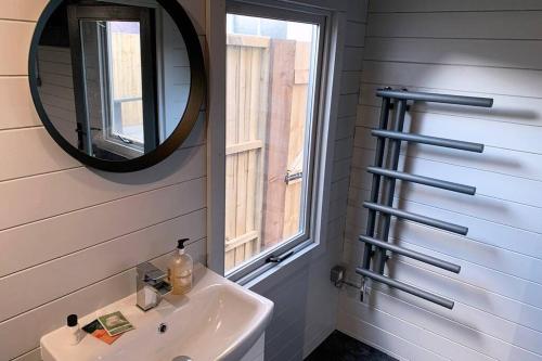 ein Bad mit einem Waschbecken und einem Spiegel in der Unterkunft Cosy, Self-Contained Garden Room in City Centre! in Hereford