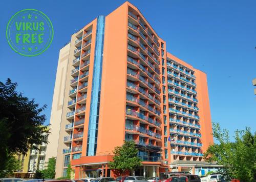 wysoki pomarańczowy budynek z samochodami zaparkowanymi na parkingu w obiekcie Hotel Shipka Beach - Free parking w Słonecznym Brzegu