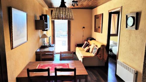 uma sala de estar com uma mesa e uma pessoa sentada num sofá em Apartamento en Font Romeu Via em Font Romeu Odeillo Via