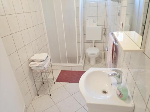 a white bathroom with a sink and a toilet at Apartments Nada in Starigrad-Paklenica