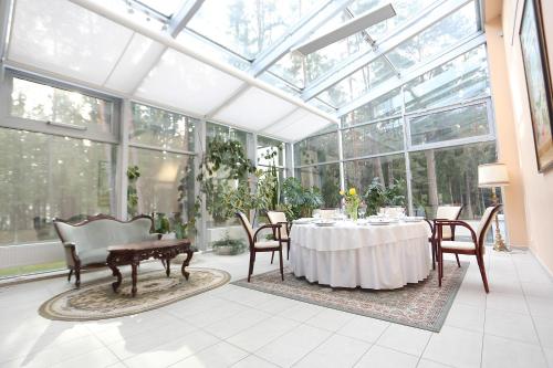 a dining room with a table in a conservatory at Royal SPA Residence in Birštonas