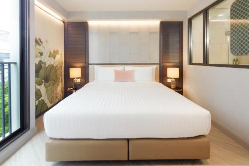 a bedroom with a large white bed with two lamps at The Quarter Ploenchit by UHG in Bangkok