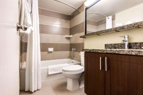 a bathroom with a toilet and a tub and a sink at Comfort Inn Airport West in Mississauga