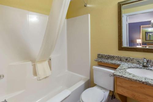 a bathroom with a toilet and a sink and a mirror at Econo Lodge Clovis in Clovis