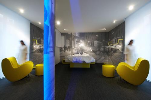 a room with a bed and yellow chairs at The Street Milano Duomo | a Design Boutique Hotel in Milan