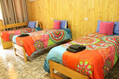 Habitación con 2 camas y mantas de colores. en Cabañas Oberá en Oberá