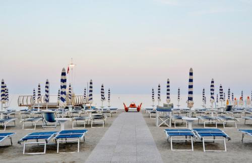 a row of chairs and tables on a beach at Hotel Tirreno in Spotorno