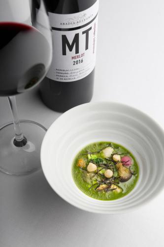 a white bowl of soup next to a bottle of wine at Abadia Retuerta LeDomaine in Sardoncillo