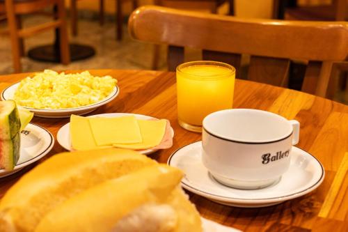 a table with plates of food and a cup of orange juice at Pompeu Rio Hotel in Rio de Janeiro