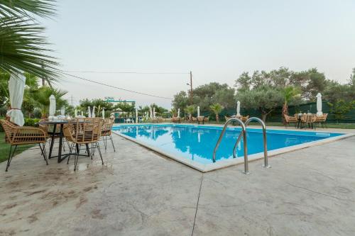 a swimming pool with a table and chairs next to it at La Terra Nostra in Korinthos