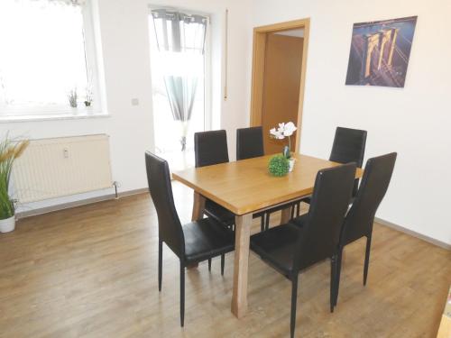 une salle à manger avec une table en bois et des chaises noires dans l'établissement SUNNYHOME Monteurwohnungen und Apartments in Wackersdorf, à Wackersdorf
