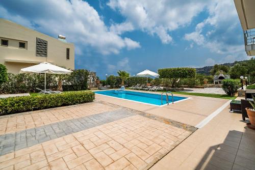 a swimming pool with umbrellas next to a building at Aroma Villas in Hersonissos