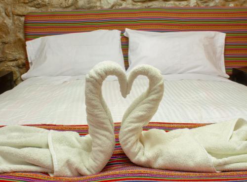 two towels shaped like swans sitting on a bed at Hostal Casa Del Inka in Cusco