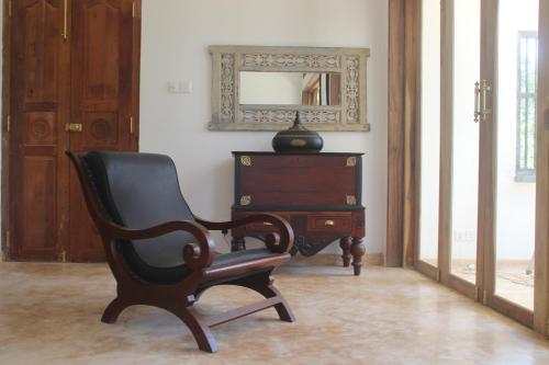 a black chair sitting next to a dresser and a mirror at The Spice House Mirissa in Mirissa