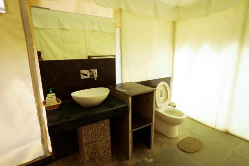 a bathroom with a sink and a toilet at Dera Baghdarrah Nature Retreat Udaipur in Udaipur